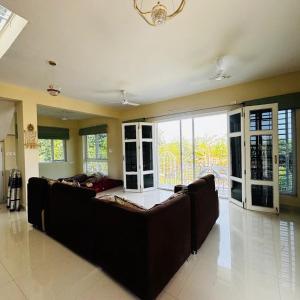 a large living room with a couch and a large window at 'Tatvamasi' Farmstay, Hillock The Nature Retreat, Vikarabad in Morangpalli