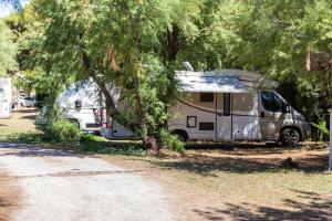 a camper parked in a field under a tree at Secret View Glamp - La Mariposa in Alghero