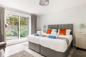 a bedroom with two beds and a large window at Middle Chine - Beautiful Garden and Spacious Living Space in Bournemouth