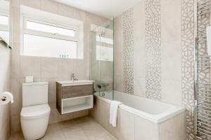 a bathroom with a toilet and a tub and a sink at Middle Chine - Beautiful Garden and Spacious Living Space in Bournemouth