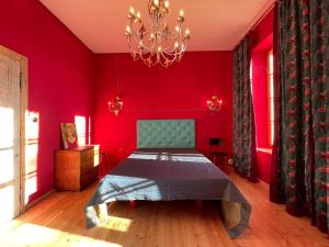 a bedroom with red walls and a bed with a chandelier at Der Schwan - Gutshaus Bückling in Rambin