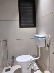a bathroom with a white toilet and a window at Hotel Atithi Lodging Pune in Pune
