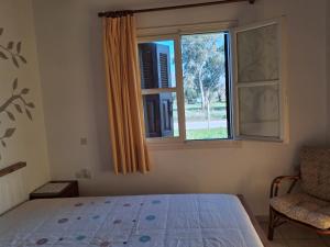 a bedroom with a bed and a window and a chair at tragano in Traganón