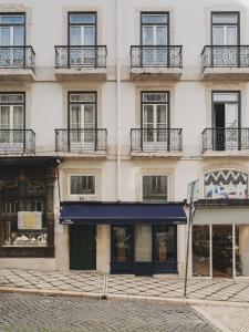 a tall building with windows and a blue awning at Casa Solayme Garrett in Lisbon