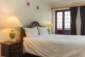 a bedroom with a bed with two lamps and a window at Northern Breeze Comfort in Ribeira Grande