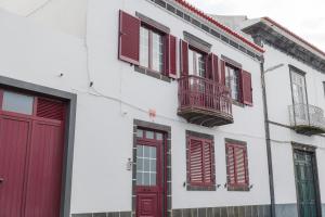 a white building with red doors and windows at Northern Breeze Comfort in Ribeira Grande