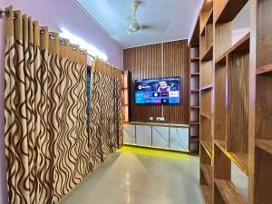 a hallway with a tv in a room with wooden walls at Richards Shared Apartment-AC in Thiruvalla