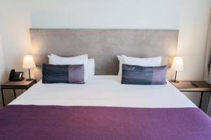 a bedroom with a large bed with purple sheets and pillows at KOS Pilar Hotel in Pilar +51 photos
