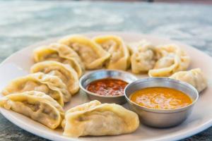 a plate of food with dumplings and dipping sauces at Hotel Saraswati in Nautanwa