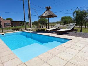 a swimming pool with two chairs and an umbrella at Quinta El Oasis ORO VERDE in Oro Verde