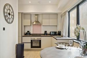 a kitchen with a table and a clock on the wall at Platform One Apartments - Caversham in Reading