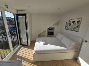 a white bed in a room with a balcony at Albion's House in Luton