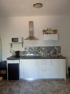 a kitchen with white cabinets and a stove top oven at Finca el Gaudi, casita Catharina in L'Ampolla