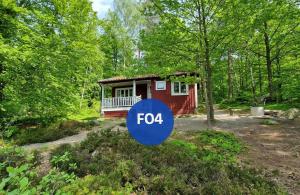 a small house in the woods with a forka sign in front at Långasjönäs Camping & Stugby in Karlshamn