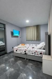 a bedroom with a bed and a flat screen tv at Peruyork Arbnb - Sol de Pimentel in Chiclayo