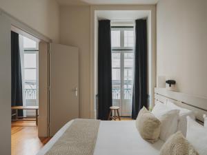 a bedroom with a large white bed and windows at Casa Solayme Vitória in Lisbon