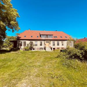 an old house with a red roof on a field at Die Orchidee - Gutshaus Bückling in Rambin