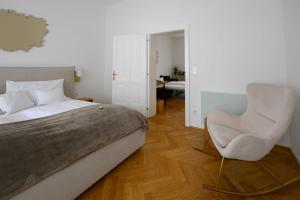 a bedroom with a bed and a white chair at Gut Purbach in Purbach am Neusiedlersee
