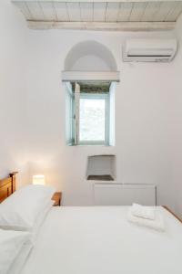 a white bedroom with a bed and a window at Axas House in Stení