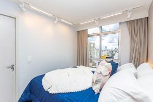 a bedroom with a blue bed and a window at Galeria Tijucas in Curitiba