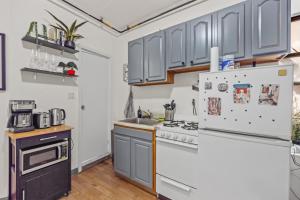a kitchen with gray cabinets and a refrigerator at Chic Times Square 1-Bedroom Apartment - Hosts 4 in New York