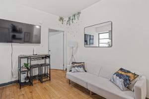 a white living room with a couch and a mirror at Chic Times Square 1-Bedroom Apartment - Hosts 4 in New York