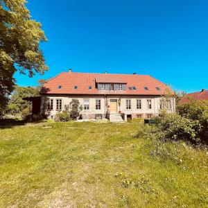 an old house with a red roof on a field at Die Perle - Gutshaus Bückling in Rambin