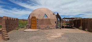 a dome house with a wooden door and a fence at Domo del desierto in San Pedro de Atacama