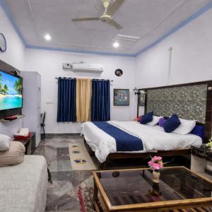 a bedroom with a bed and a tv and a couch at Eastern Gate Homestay in Khajurāho