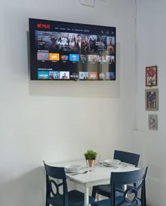 a white table with chairs and a tv on the wall at Mini Bamboo Nest con Desayuno in Puyo