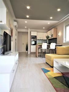 a living room with a yellow couch and a kitchen at Apartments Villa Vujcic in Makarska