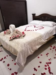 a bed with red rose petals on the floor at HOTEL El MONARCA in Tunja +13 photos