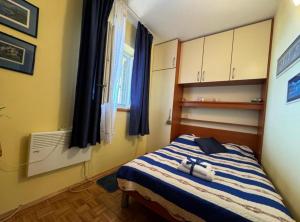 a bedroom with a bed with a blue and white blanket at Family Apartment Sofija in Preko