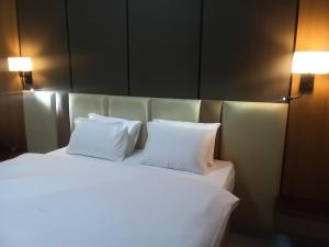 a white bed with two pillows on top of it at Ghomes in Lagos