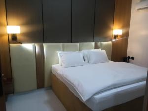 a bed with white sheets and pillows in a room at Ghomes in Lagos