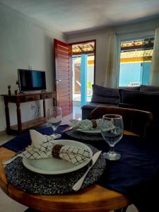 a table with two plates and wine glasses on it at Luz Residence beach house in Cabo Frio