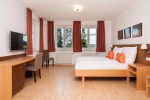 a hotel room with a bed and a desk with a computer at Haus Steirer am Kaiserwald in Premstätten