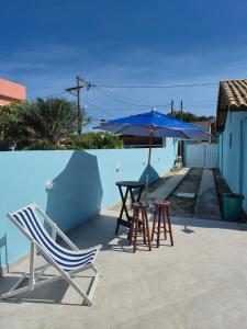 a patio with a table and chairs and an umbrella at Luz Residence beach house in Cabo Frio