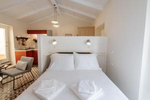a bedroom with a white bed and a chair at Kamari Guest House Corfu in Corfu International Airport I Kapodistrias