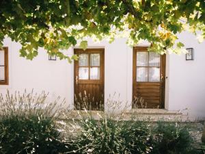 a white house with wooden doors and trees at Gut Purbach in Purbach am Neusiedlersee