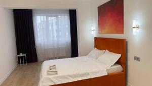 a bedroom with a bed with white sheets and a window at Aspan City Comfort 3 in Pokrovka +6 photos