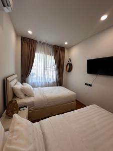 a hotel room with two beds and a flat screen tv at Patong Relax Home in Patong Beach