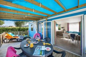a blue house with a table and chairs on a deck at ZEcamping 4 étoiles familial avec piscine couverte in Laroque-des-Albères