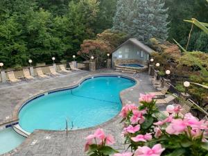 a swimming pool with chairs and pink flowers at Misty Mountain Condo by Beyond Expectations- 3BR Retreat with Scenic Views, Sleeps 8 & Near Ober Mountain in Gatlinburg