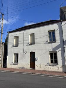 a white building with a door and three windows at Le Clemenceau - Appartements meublés in Gien