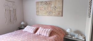 a bedroom with a bed with two pink pillows at Chambre la Bohème in Élancourt