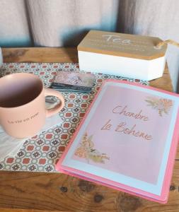 a table with a cup of coffee and a box at Chambre la Bohème in Élancourt +1 photo