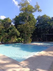 a blue swimming pool with trees in the background at Hotel Tré Iguazú in Puerto Iguazú
