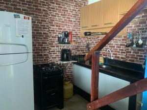 a kitchen with a white refrigerator and a brick wall at casa aconchegante proximo a praia in Maceió