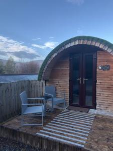 a brick building with two chairs and a door at Woodside Round Pod in Fort William